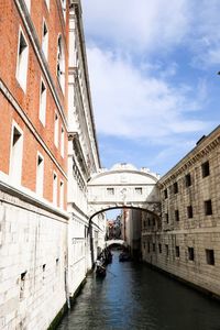 Canal amidst buildings in city against sky