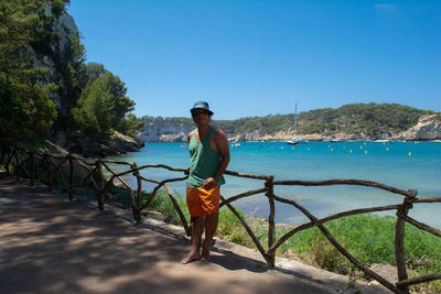 Full length of man standing on sea against clear blue sky