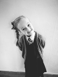 Portrait of smiling girl standing against wall