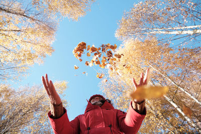 Low angle view of man standing by tree against sky