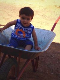 Portrait of cute boy sitting on land