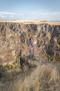 Man standing on rock against sky