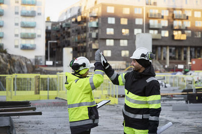 Construction engineers high-fiving at construction site