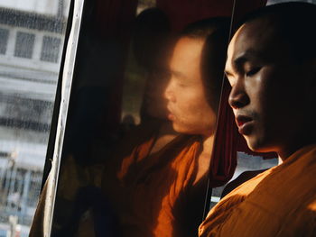 Close-up of monk sleeping while traveling in bus