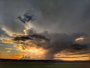Scenic view of dramatic sky over land during sunset