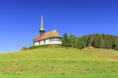 Built structure on field against clear blue sky