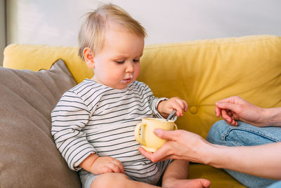 Portrait of cute baby girl sitting on sofa at home