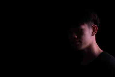 Side view of young man against black background