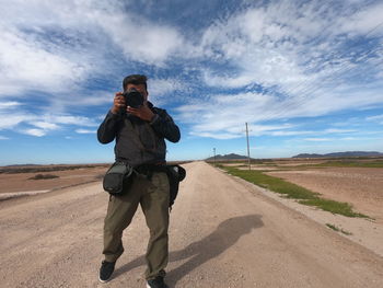 Man photographing on desert against sky