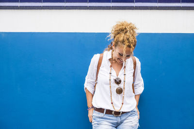 Portrait of woman standing against blue wall