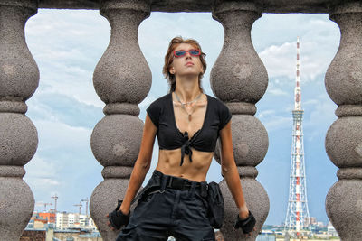 Portrait of young woman standing against sky