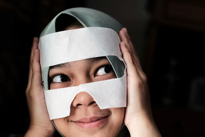 Close-up of woman with face covered by tape against black background