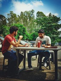 Friends sitting on table against trees