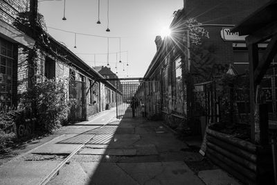 Footpath amidst houses against sky on sunny day