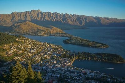 Aerial view of sea and mountains against clear blue sky