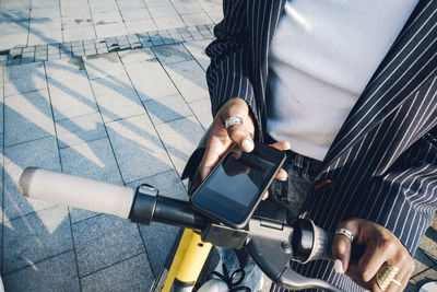 Businesswoman paying online for electric push scooter in city