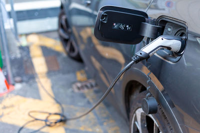 A cable is recharging an electric car at the charging station