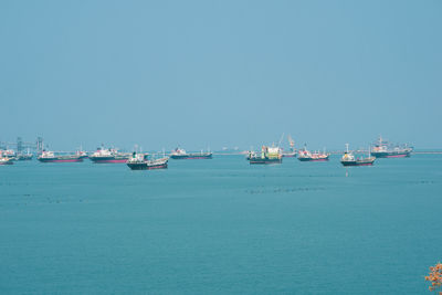 Boats in sea against clear blue sky