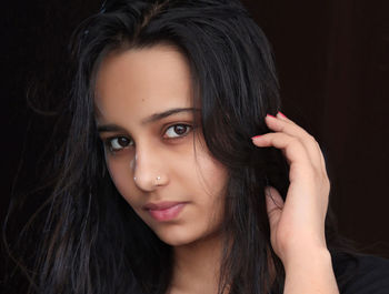 Close-up portrait of a beautiful young woman over black background