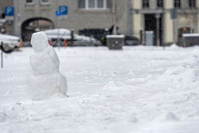 Snowman in the yard of a residential house, isolated on a defocused city background