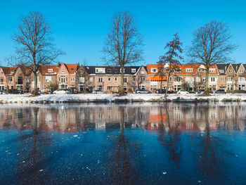 Canal by buildings against blue sky