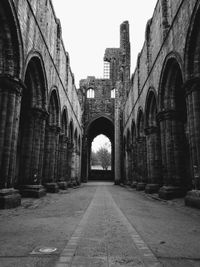 Diminishing perspective of footpath amidst old ruin against clear sky