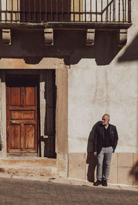 Man in black suit standing against old building