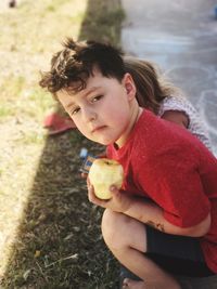 Portrait of boy with sister holding apple on field