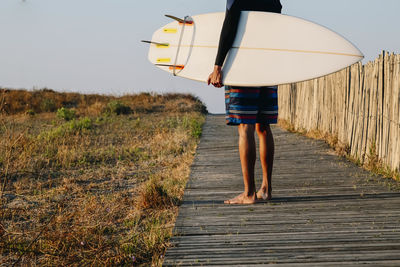 Surfer holds a surfboard when the beach dawns, extreme sport, healthy and exercising.