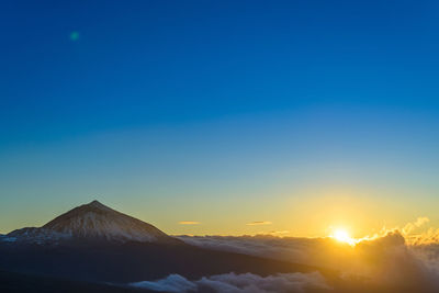 Scenic view of snowcapped mountains against clear sky during sunset