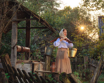 A village young peasant woman is engaged in work in the morning early carries water from the well