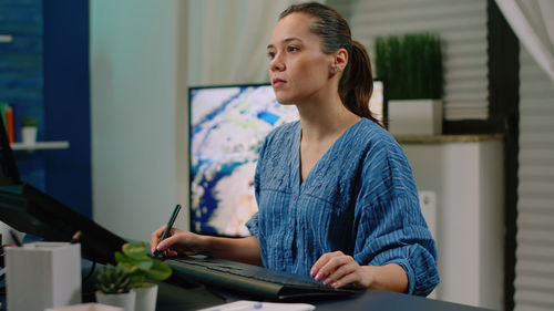 Young woman using mobile phone while sitting on table