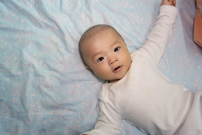 Portrait of cute baby lying on bed