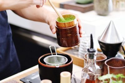 Midsection of person pouring tea cup on table