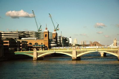 Bridge over river in city against sky
