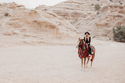 Young woman riding horse at desert