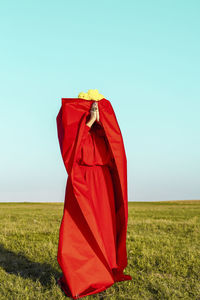 Red umbrella on field against sky