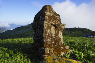 Cross on field against sky