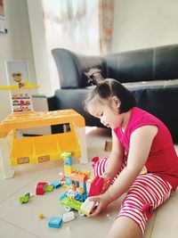 Woman holding toy while sitting on table at home