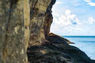 Rock formation by sea against sky