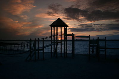 Volleyball net and monkey bars at beach during sunset