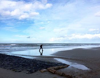 Man walking at beach against sky