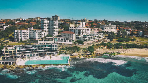 Buildings by sea against blue sky