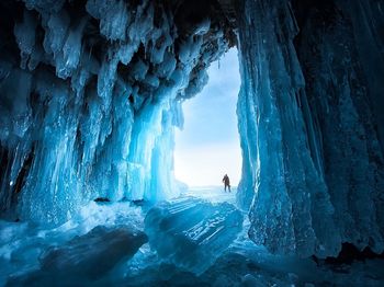 Distant view of man standing in frozen cave