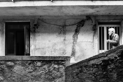 Man standing by window of old building