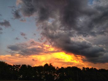 Low angle view of silhouette trees against dramatic sky