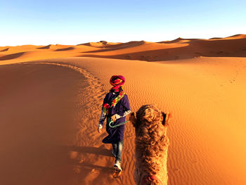 Man standing on sand dune in desert against sky