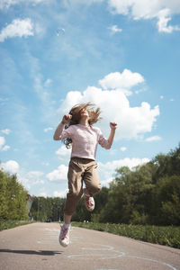 Rear view of boy running on road against sky