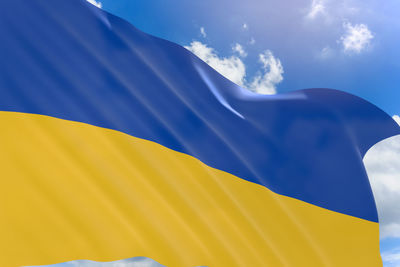 Low angle view of yellow flag against blue sky