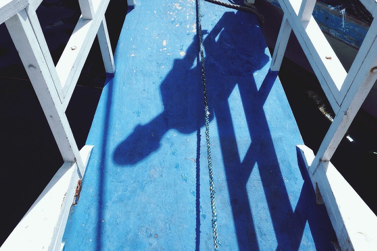 shadow, sunlight, fence, lifestyles, focus on shadow, leisure activity, railing, blue, day, outdoors, city life, outline